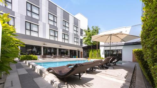 a hotel pool with lounge chairs and an umbrella at Gate43 Airport Hotel in Lat Krabang