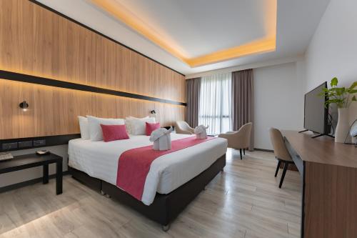 a hotel room with a large bed and a television at Gate43 Airport Hotel in Lat Krabang