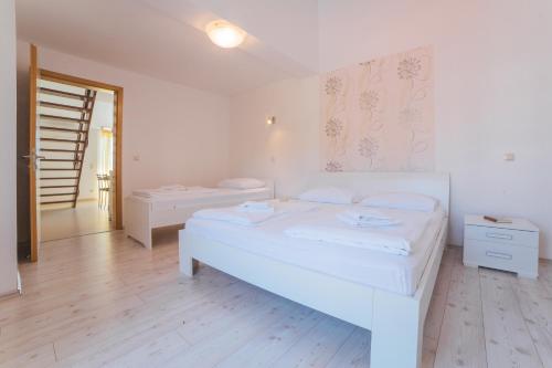 a white bedroom with two beds and a staircase at Apartments Sea View in Omiš