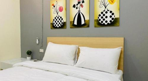a bedroom with four paintings on the wall at Sweet Hug Hotel in Suphan Buri