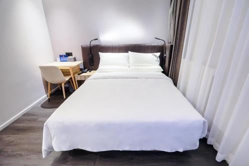 a bedroom with a large white bed and a desk at Hanting Hotel Beijing South Railway Station Center in Beijing
