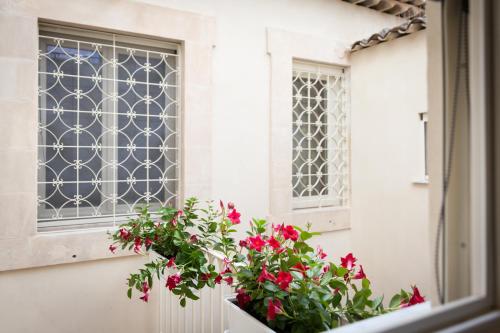 a window with red flowers on a window sill at Palazzo Montalbano in Scicli