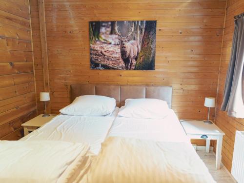 two beds in a room with a picture of a deer at Chalet in Manhay for 9 Person in Manhay