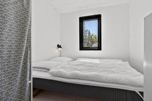 a white bedroom with a bed with a window at 8804-Glesborg-Vesttoften-20 in Glesborg