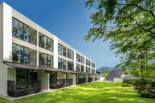 an exterior view of a building with a yard at Holiday Inn Resort Shinano-Omachi Kuroyon by IHG in Omachi