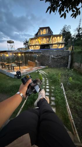 a person taking a picture of a house with a camera at Himadvaya- The Himalayan Prism in Almora