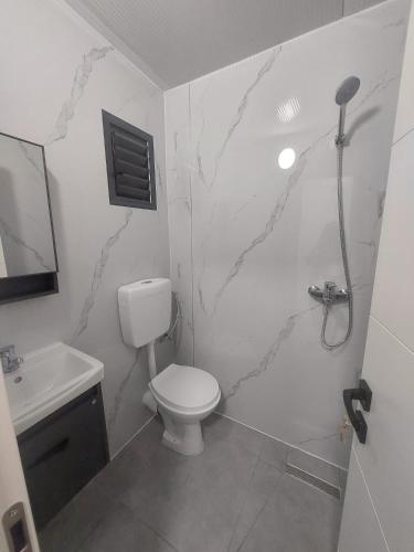 a white bathroom with a toilet and a sink at בקתה על הנחל in Yuval