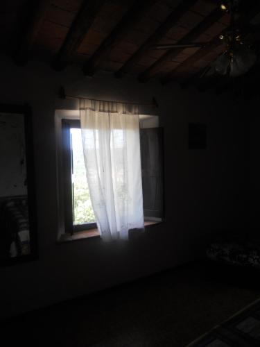 a window with a white curtain in a dark room at Tenuta Il Tresto in Poggibonsi