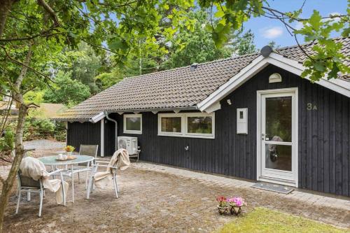 a black shed with a table and chairs in front of it at 946-Frederiksvaerk-Skelvaenget-3-a in Frederiksværk