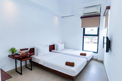 two beds in a room with a table and a window at Onederz Phnom Penh in Phnom Penh