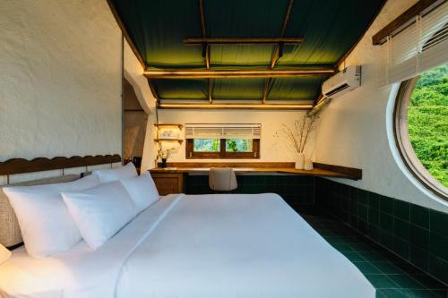 een slaapkamer met een groot wit bed met een raam bij Paradise Retreat Hon Son in Lai Sơn