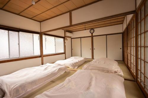 Dos camas en una habitación grande con ventanas. en キッチンが使いやすい田舎の一棟貸, en Yamaguchi