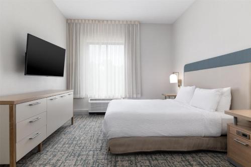 a hotel room with a bed and a flat screen tv at Homewood Suites by Hilton Baltimore - Arundel Mills in Hanover