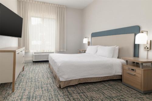 a hotel room with a bed and a flat screen tv at Homewood Suites by Hilton Baltimore - Arundel Mills in Hanover