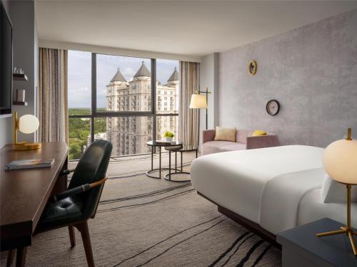 a hotel room with a bed and a desk and a large window at The Starling Atlanta Midtown, Curio Collection by Hilton in Atlanta