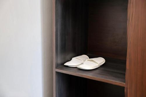 two white shoes sitting on a wooden shelf at Kelingking Tropical in batumadeg