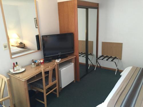 a room with a television on a desk with a bed at Crystal Palace Hotel in Montevideo