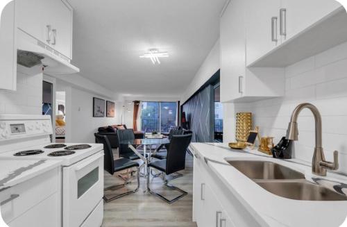 a white kitchen with a sink and a table at 17th Ave Cozy Nest in Downtown Calgary with Parking in Calgary