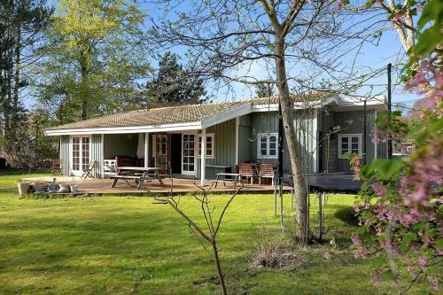 a green house with a picnic table in the yard at 12228-Sjaellands-Odde-Strandvaenget-23 in Yderby