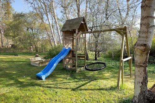 a playground with a blue slide and a tree at 12228-Sjaellands-Odde-Strandvaenget-23 in Yderby