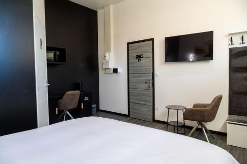 a bedroom with a bed and two chairs and a tv at SEE - Gare de Marly in Valenciennes