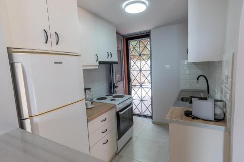 a kitchen with white cabinets and a white refrigerator at Balcone Ionico in Agios Andreas Ilias