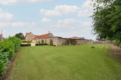 un gran patio de césped con casas al fondo en Quaint converted stables in Carlby, en Carlby