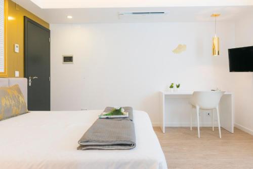 a bedroom with a white bed and a table at Sport Hotel A Seleção in Setúbal