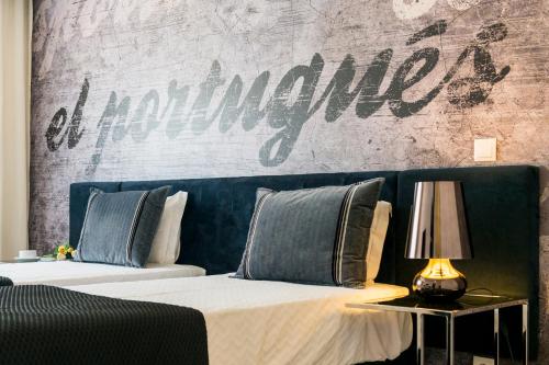 a bedroom with two beds and a wall with the wordania at Sport Hotel A Seleção in Setúbal