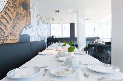a long table with white plates and silverware on it at Sport Hotel A Seleção in Setúbal