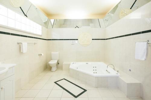 Un baño blanco con bañera y inodoro. en Lake Hume Resort, en Lake Hume