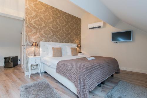 a bedroom with a bed and a tv on a wall at Boutique Hotel Caelus VII in Tongeren