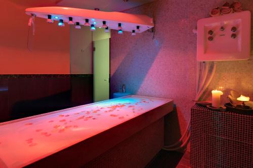 a pink bathroom with a mirror and lights at Hotel Federico II in Iesi