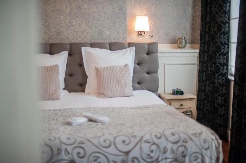 een slaapkamer met een groot wit bed met kussens bij Boutique Hotel Caelus VII in Tongeren