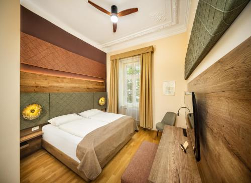 a bedroom with a bed and a ceiling fan at Das Gutenbrunn Thermen & Sporthotel in Baden