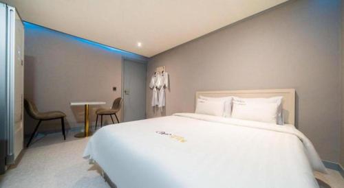 a bedroom with a large white bed and a table at Chuncheon World Hotel in Chuncheon