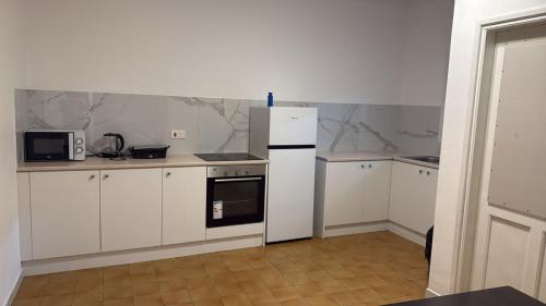 a kitchen with white cabinets and a white refrigerator at Downtown Rooms, 200m from Marina Beach in Larnaka
