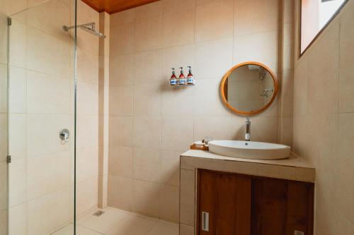 Un baño con lavabo y ducha con espejo. en Kubu Wana Villa, en Uluwatu