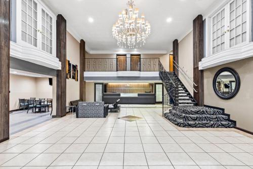 a lobby with a staircase and a chandelier at Baymont by Wyndham Port Arthur - Groves Area in Port Arthur