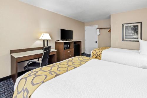 a hotel room with two beds and a desk at Baymont by Wyndham Port Arthur - Groves Area in Port Arthur
