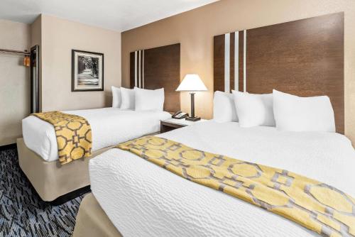 a hotel room with two beds and a chair at Baymont by Wyndham Port Arthur - Groves Area in Port Arthur
