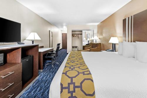 a hotel room with a large bed and a desk at Baymont by Wyndham Port Arthur - Groves Area in Port Arthur