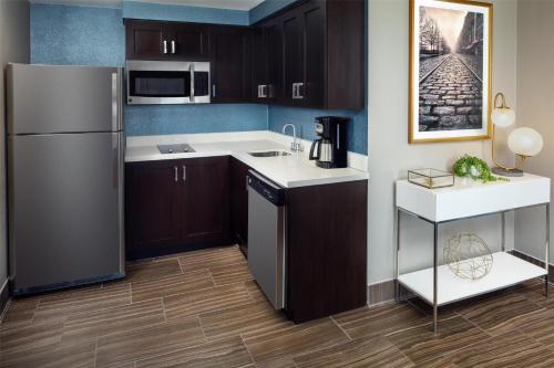 a kitchen with brown cabinets and a refrigerator at Homewood Suites Savannah Historic District/Riverfront in Savannah