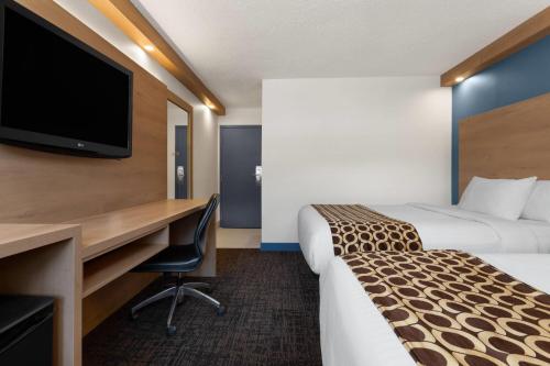 a hotel room with two beds and a desk and a tv at Travelodge by Wyndham Blairmore in Blairmore