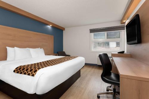 a hotel room with a bed and a desk with a computer at Travelodge by Wyndham Blairmore in Blairmore