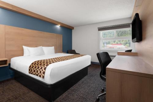 a hotel room with a bed and a desk and a television at Travelodge by Wyndham Blairmore in Blairmore