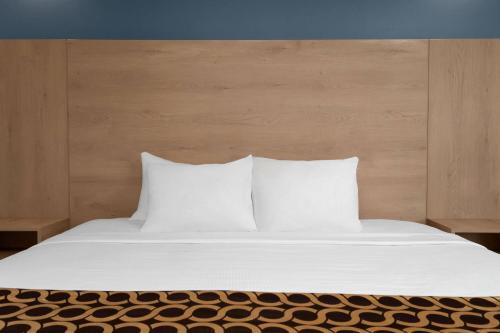 a bed with white sheets and pillows on it at Travelodge by Wyndham Blairmore in Blairmore