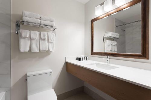 a white bathroom with a sink and a mirror at Travelodge by Wyndham Blairmore in Blairmore