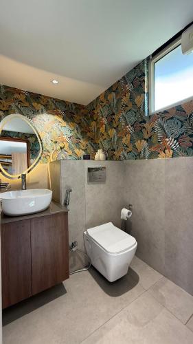 a bathroom with a sink and a toilet and a mirror at Himadvaya- The Himalayan Prism in Almora