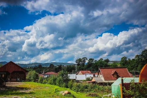 a group of houses in a field with a cloudy sky at Casa Daya in Topliţa